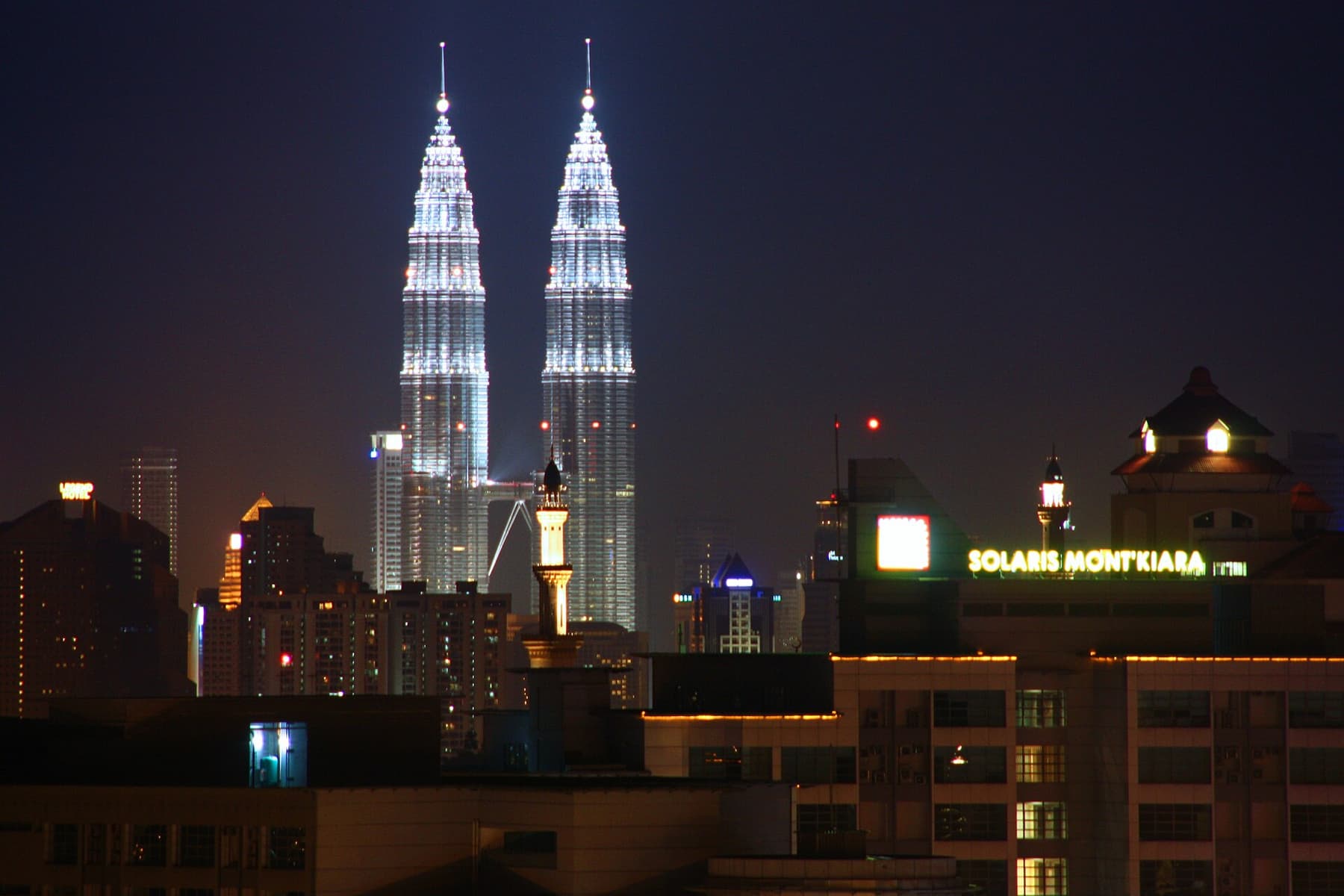 The Kuala Lumpur skyline lit up at night with the Petronas Towers